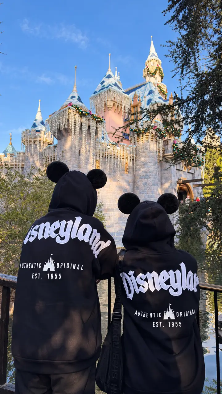 Two people seen from behind wearing the magnetic ears on a park day